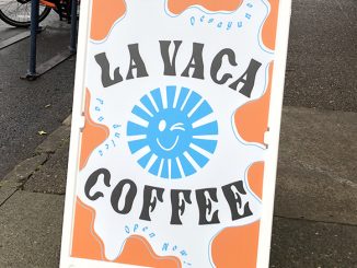 The sign La Vaca coffee in bright colorful writing on the sidewalk.