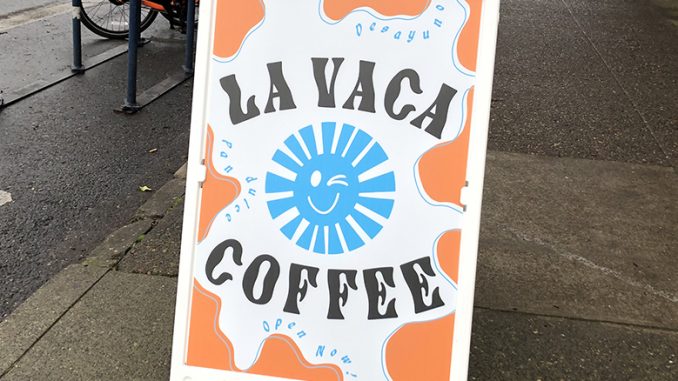 The sign La Vaca coffee in bright colorful writing on the sidewalk.