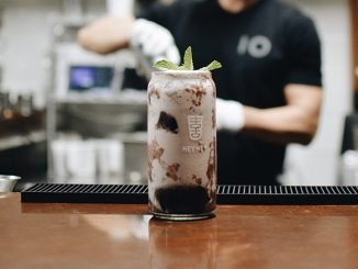 An image of a boba beverage in a cocktail glass. Behind stands a bartender of Hey Hey blurred out while mixing a drink.