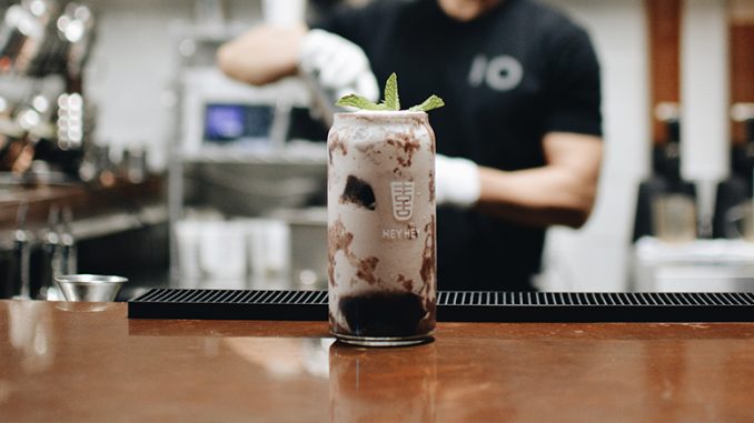 An image of a boba beverage in a cocktail glass. Behind stands a bartender of Hey Hey blurred out while mixing a drink.