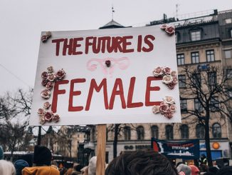 a scene of a women's march. a woman holds a sign that says the future is female.