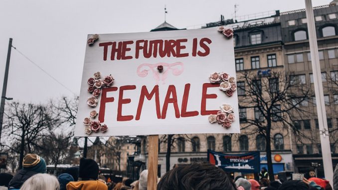 a scene of a women's march. a woman holds a sign that says the future is female.