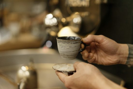 A closeup of a hand holding a ceramic mug.