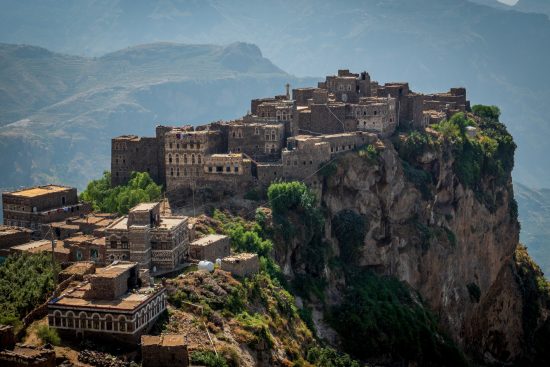 A mountain landscape of Yemen shows clustered buildings sitting on top of a mountain.