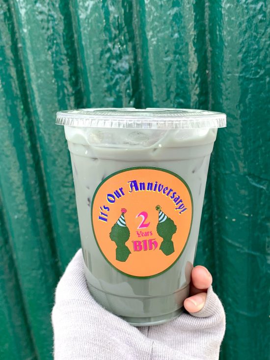 A closeup of a plastic cup holding a green iced drink.