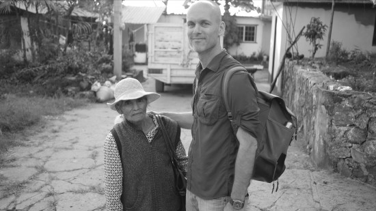 Michael stands with a coffee producer in a black and white photo.