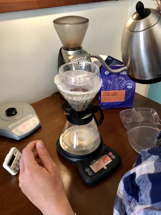 A gooseneck kettle pours water into a v60 with the drip assist sitting on top.