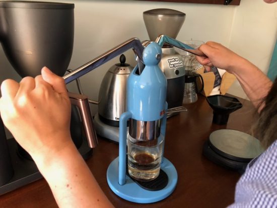 Two hands pressing down on the levers of the cafelat.