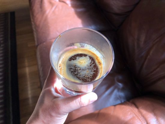 Holding the shot of espresso by the cafelat. It is light with crema and in the sunlight.