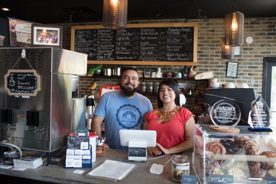 The owners of back of the yards smiling behind the counter of their shop.