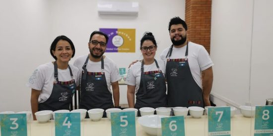 A group stands together smiling while judging coffees.