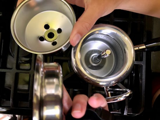 Opening the inside of the stovetop steamer, closeup holding three different parts.