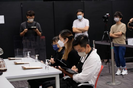 Gary writes on a clipboard sitting at a judges table.