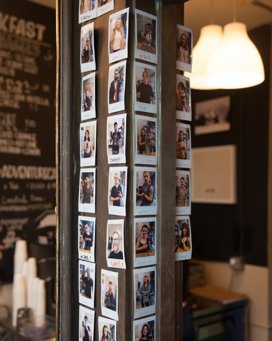 A pillar inside a coffee shop with polaroids of people who subscribed to the cafe membership model.