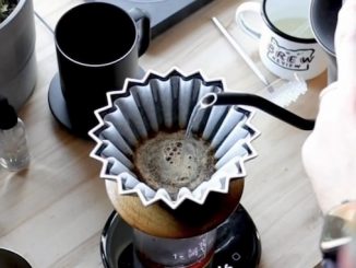 A closeup of a hand pouring water over a pourigami coffee cone.