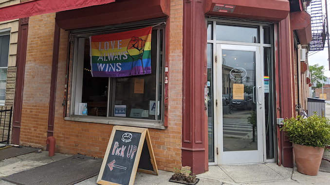 The front of a coffee shop in new york city with a sign for a pickup window.