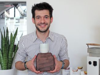 Alessandro is an Italian white male who sits smiling holding a plaque with his latte art champion trophy.