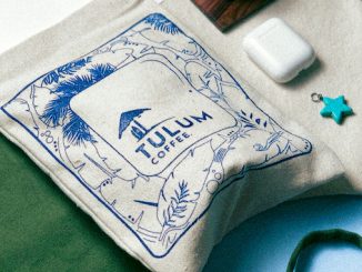 A bag of cloth holds coffee beans with the Tulum logo.