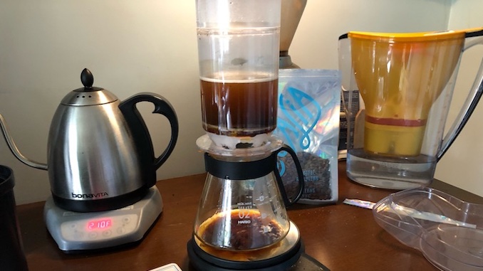 The plastic tricolate brewer in the middle of brewing coffee.