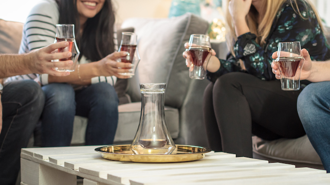 The lower halves of four people hold up Kruve glasses with coffee.