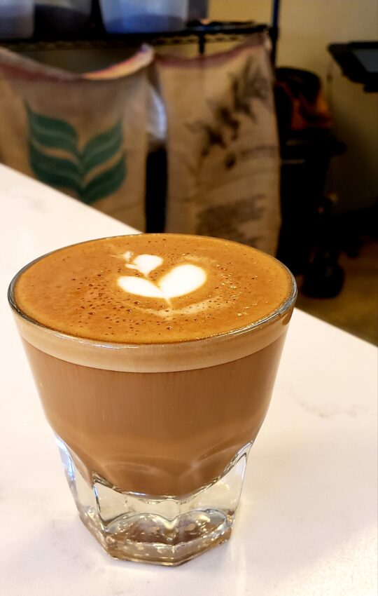 A cortado with a hint of latte art on a counter in a cafe.