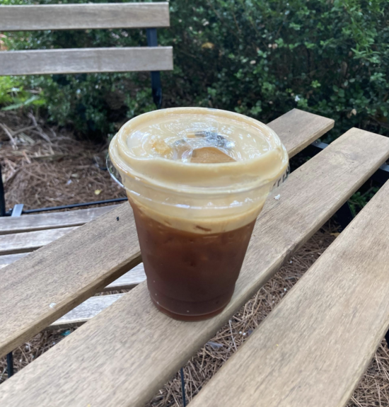 Ένα Espresso Tonic σε ένα to-go cup σε ένα παγκάκι στο Rosie's Coffee and Wine Garden στο Charlotte, NC