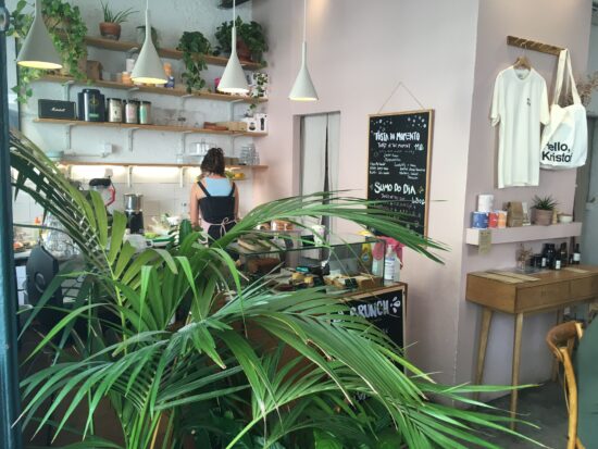 Крупный план пальмовых листьев внутри кафе.  Стойка и доска меню позади.