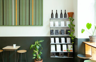 A wall of Isla Coffee featuring shelves of retail wine and coffee.  To the left is a potted plant and some striped wall art.
