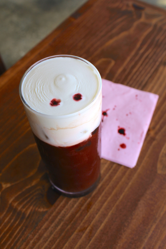 A red velvet iced coffee drink that looks like blood with sweet cream topping and "blood" sprinkle.