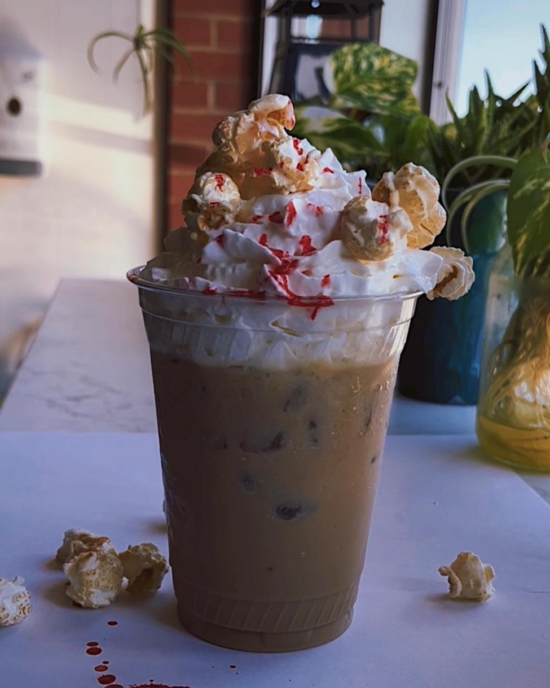 An iced latte with whipped cream, topped with kettle corn and "blood" splatter syrup.