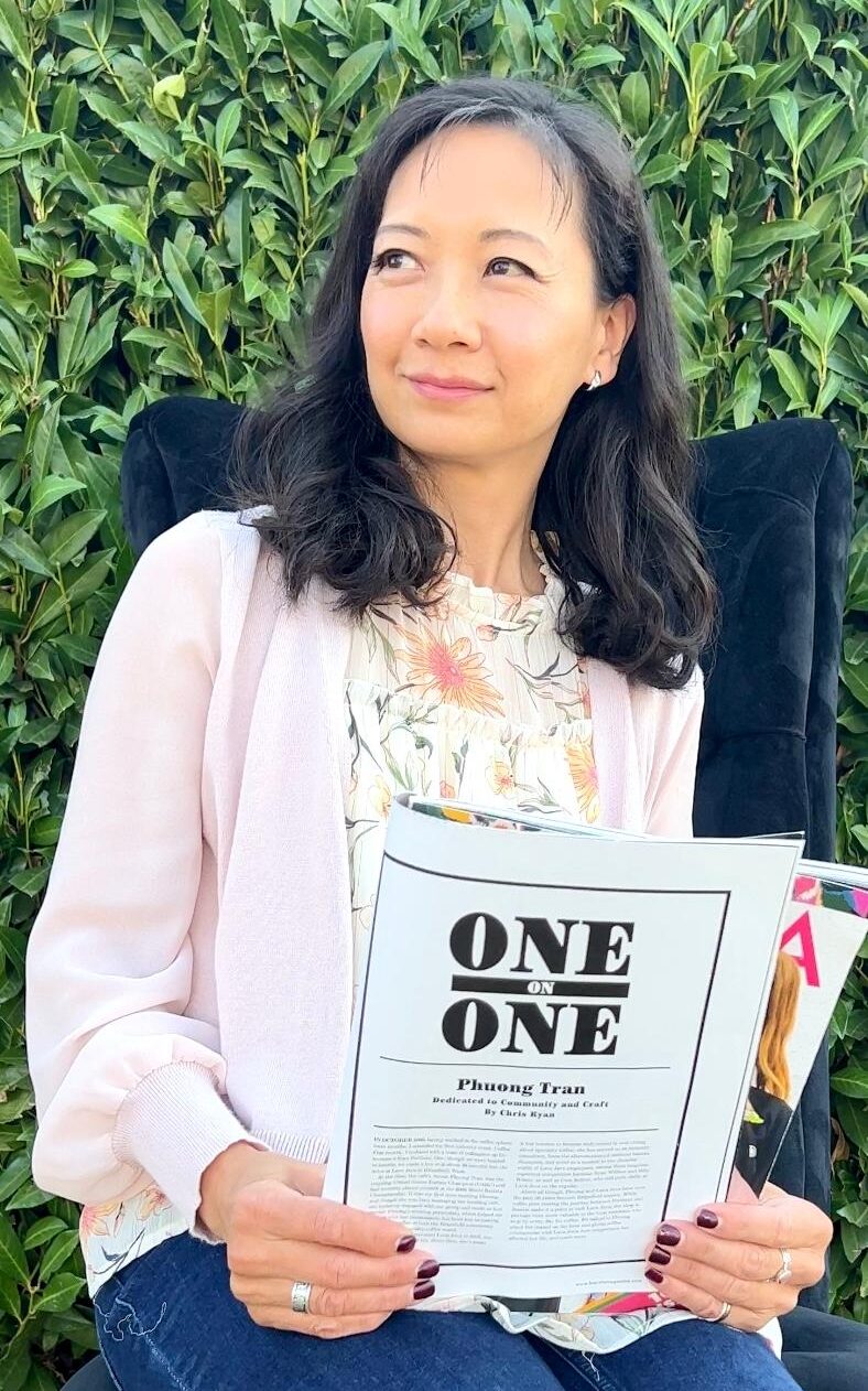 Phuong is seated, holding a copy of Barista Magazine featuring herself. 