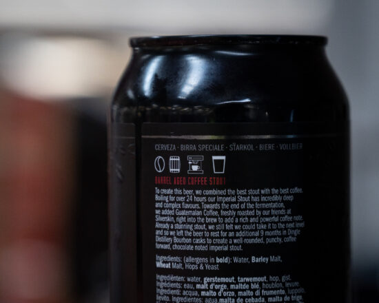 The back of the coffee stout can explains the brewing process and lists ingredients. It has small symbols indicating a coffee bean, wooden barrel, espresso machine and beer glass.