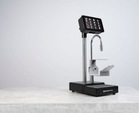 Image of LAF Bar Pro. This has the display screen on top of a metal rod, with a drain at the bottom on the stand. The steaming wand runs up and under the screen. There is a little lever under it to hold up steaming pitchers.
