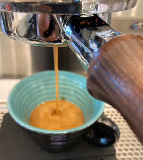 Espresso pouring from the grouphead directly into a blue mug with a light blue interior.