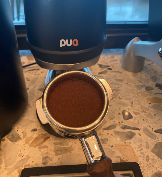 Espresso tamped in the portafilter evenly with a Puqpress.