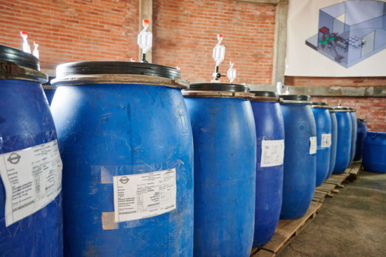 Blue tanks are lined neatly against a brick wall on wooden pallets. They each have a valve on top for pumping in CO2. 