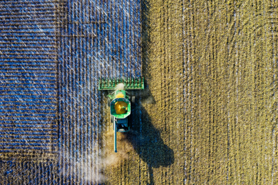An overhead, maybe fifty feet up, view of a tractor harvesting a blue crop.