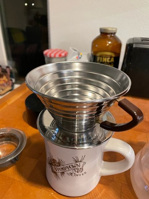 A Kalita Wave pourover device. It sits on top of a Stumptown Coffee diner mug on a kitchen counter in front of a toaster.