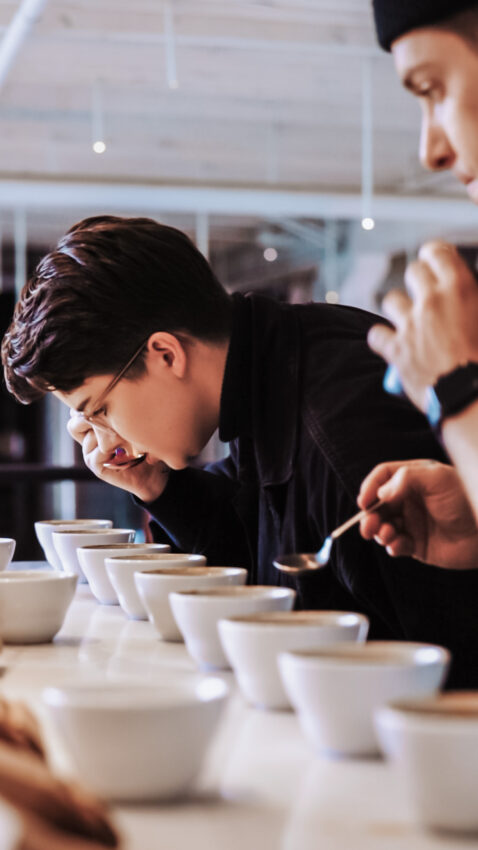 Morgan and another competitor sip coffee from spoons during a cupping.