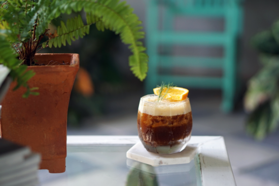 Orange chai soda in a glass served with slice of orange.