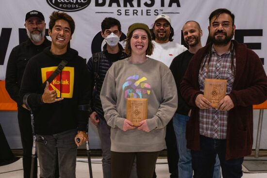 The three finalists pose with their wooden plaques. Kimhak gives a shaka hand or hang ten sign with thumb and pinkie extended, three middle fingers curled against the palm. He wears elbow crutches and a Kodak hoodie. Kiara in the middle wearsa gray sweatshirt and green beanie. Steve wears a beard, flannel shirt and snazzy brown cardigan.