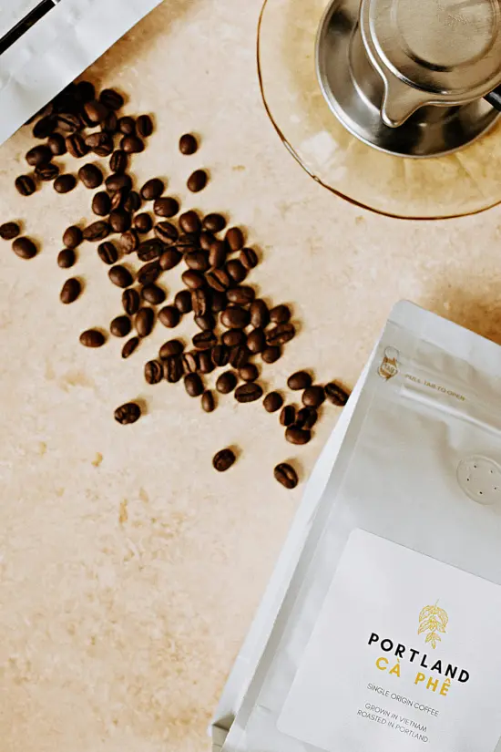 A Portland Ca Phe bag, a single origin grown in Vietnam. A phin filter is behind it on the counter, with some espresso beans spilled out of a second bag.
