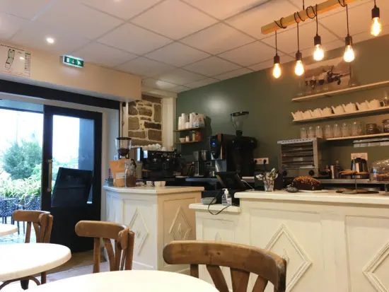 Interior of Folks, with a french country feel of soft white paint, warm lighting and woode and brick accents. Open shelving is on the wall behind the white wooden countertop.