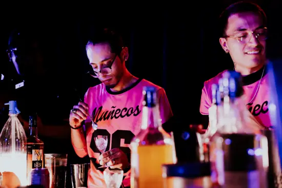 Enrique and Sebastian work the bar in the Barista League competition in Mexico City. They wear pink and black jerseys with the word Muñecos and the number 96 on the front.