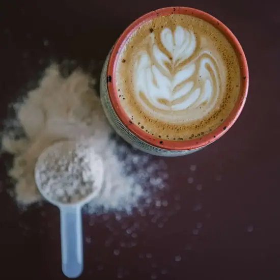 A rice milk drink in a mug with rice powder on the counter next to it.