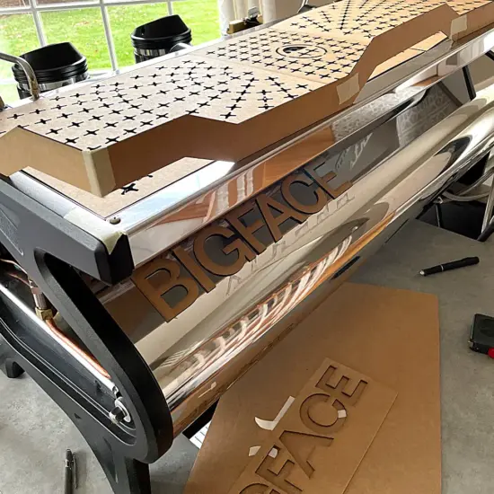 A Strada espresso machine with cardboard cutouts on top for a design pattern test, and cardboard lettering on the side.