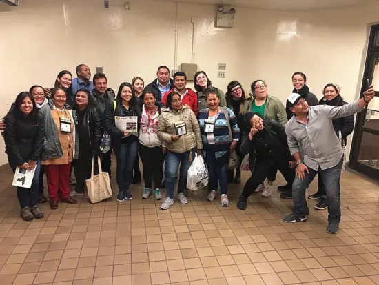 A large group of men and women pose together for a photo at a WICP panel. Some are wearing lanyards with badges on them.