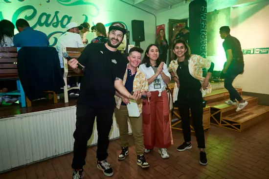 Jan poses with the three winning baristas from the la Rumba competition. Two wear bright yellow hawaiian shirts, and one wears orange wide leg pants.