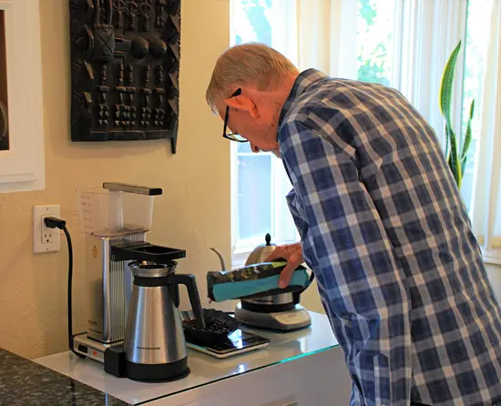 Kenneth Davids pouring coffee beans onto a scale next to his Moccamaster.