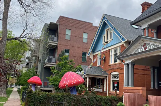 The exterior of Plant Magic has inflatable red mushrooms. The building is a red brick house with decorative windows and a covered porch.